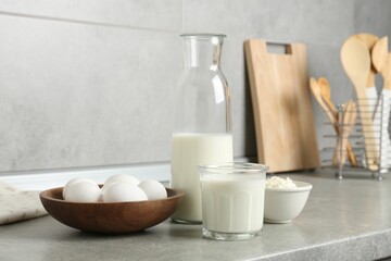 Different dairy products and eggs on gray textured table in kitchen
