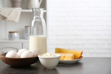 Different dairy products and eggs on gray textured table in kitchen