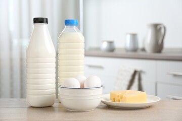 Different dairy products and eggs on wooden table in kitchen