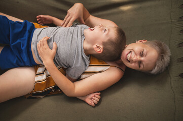 Emotional Mother and son are fooling around in a hammock in the summer forest. Family outdoor...