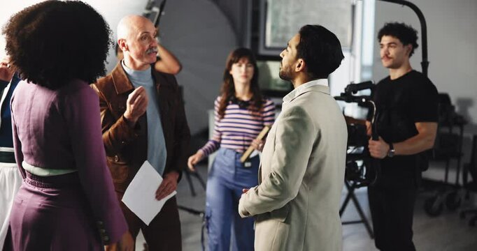 Director, actor and instructions with script for video production, commercial or filmmaking. People, crew and cast listening with producer assistance for acting help, tips or recording scene on set