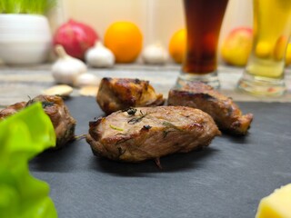 Delicious pieces of shish kebab lie on a sliced board. There are glasses of dark and light beer in...