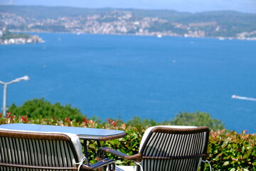 Garden table and chairs overlooking the Bosphorus. A crow with bread in its mouth is perched on the table. Enjoy the view of the greenery and blue Bosphorus. Garden furniture. Bosphorus - Turkey.