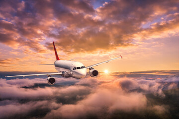 Airplane is flying above the clouds at sunset in summer. Landscape with passenger airplane,...