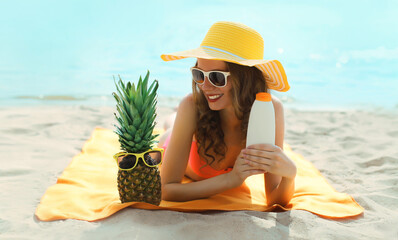 Summer vacation, happy smiling woman in tourist hat with suntan cream, lying on the beach on sea