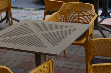 Outdoor cafe setting with yellow chairs and a square table