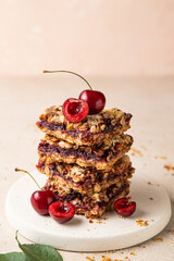Stack of baked oatmeal crumble squares with fresh cherry. Cherry oatmeal crumble bars. Quick and...