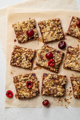 Cherry oatmeal crumble bars. Backed cherry crisp. Quick and easy homemade sweet red berry squares with streusel. Crumble fruit cake or pie. Wholesome and healthy breakfast. Home cooking. Top view.