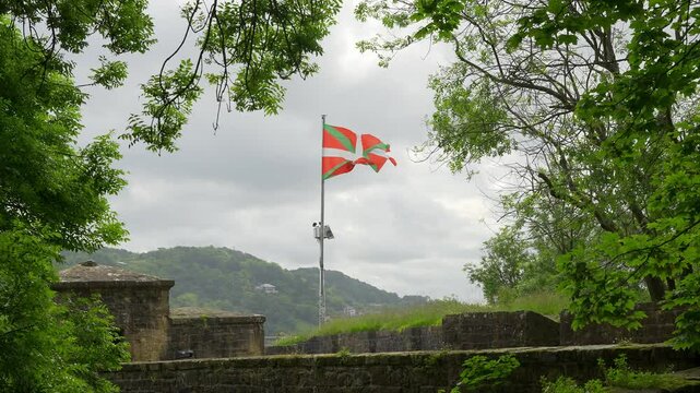 Flag of the Basque Country waving at the top of Mount Urgull next to the city of San Sebastian.