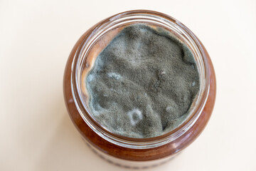 Open jar with sweet jam and mold on a white background. Mold in a jar of raspberry jam. Hazardous to health. 