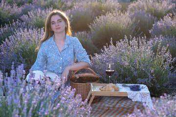 Young woman kneeling in lavender field touching flowers