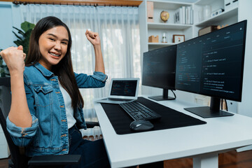 Young Asian IT developer creating raising fist up with successful information on pc with coding...