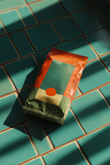 Colorful packaging of a coffee bag placed on a turquoise tiled surfac
