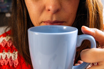 A relaxed and smiling Latina girl with a cup of coffee or cocoa at a table in her home. Concept of...