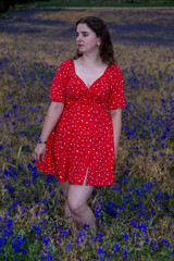 Beautiful woman posing in red dress in purple flower field at sunset