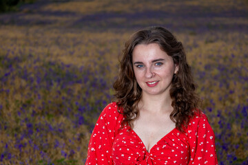 Beautiful woman posing in red dress in purple flower field at sunset