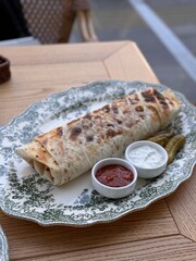 Grilled Wrap Served with Sauces and Pickles on Elegant Plate