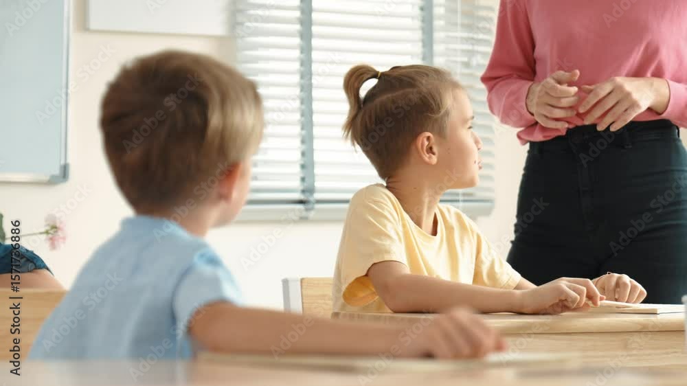 Poster beautiful teacher explaining test while caucasian boy doing classwork and listening explanation. cut