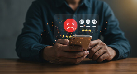 Person using smartphone with angry feedback icon and stars for rating on a wooden surface