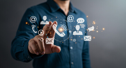 Man touching digital contact icons with phone email and social media symbols in the air around him