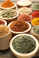 Different aromatic spices in bowls on wooden table, closeup