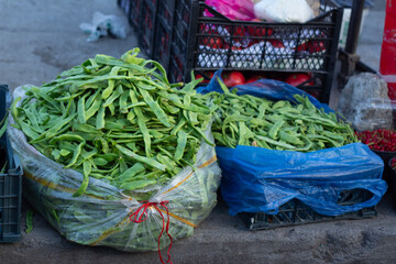 Horizontal photo. Bag of tasty ripe fresh raw green beans for making Georgian dish lobio on counter of farm street city market stall. Grocery shop. Harvest season in Georgia. Vegetable and fruit store