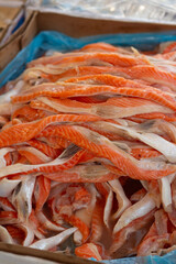 Vertical photo. Pieces of tasty ripe fresh raw red fish. Shelf with sliced ​​trout on counter of farm street city market stall. Grocery shop. Seafood store. Concept of healthy food, lunch, eat, sale