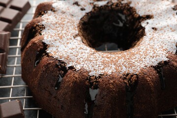 Tasty bundt cake with glaze and chocolate pieces on grey table, closeup