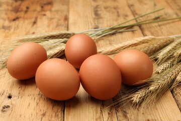 Fresh eggs and spikes on wooden table, closeup