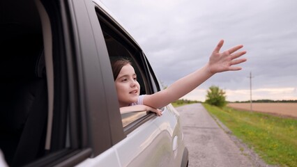 Child passenger enjoying ride. Little girl waving from car window. Child riding with family in car...