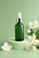 Cosmetic product and jasmine flowers on green background