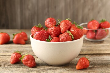 Fresh ripe strawberries in bowl on wooden table, closeup