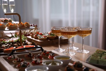 Buffet menu. Glasses of sparkling wine and tasty appetizers on table, closeup