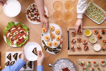 Buffet menu. People taking tasty appetizers from wooden table, top view