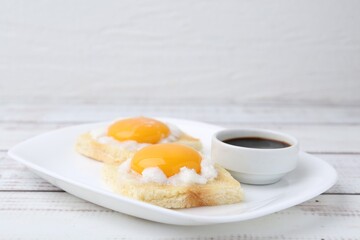 Tasty kaya toasts with half-boiled eggs served on white wooden table, closeup. Traditional asian...