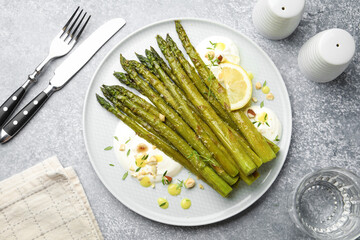 Tasty cooked asparagus served with lemon and sauce on grey table, flat lay
