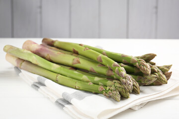Fresh raw asparagus spears on white wooden table, closeup