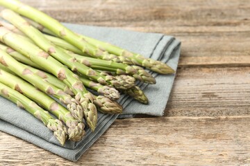 Fresh raw asparagus spears on wooden table, closeup. Space for text