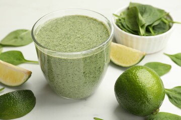Tasty spinach smoothie and ingredients on white table, closeup