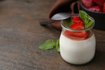Tasty panna cotta with caramel, strawberries and mint on wooden table, closeup. Space for text