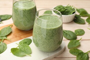 Tasty smoothie and spinach leaves on white wooden, closeup
