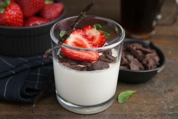 Tasty panna cotta with chocolate, strawberries, mint and vanilla pods on wooden table, closeup