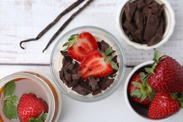 Tasty panna cotta with chocolate, strawberries, vanilla pods and caramel on white wooden table,...