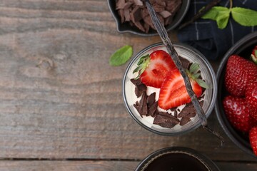 Tasty panna cotta with chocolate, strawberries, mint, vanilla pods and tea on wooden table, flat...