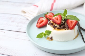 Tasty panna cotta with chocolate, strawberries, mint, caramel and vanilla pods on white wooden...