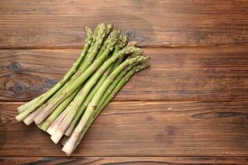 Fresh raw asparagus on wooden table, top view. Space for text