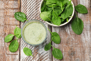Tasty smoothie and spinach leaves on wooden table, flat lay