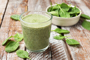 Tasty smoothie and spinach leaves on wooden table, closeup