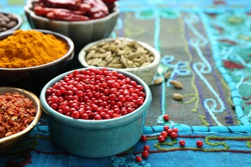 Many different aromatic spices in bowls on table with cloth, closeup. Space for text
