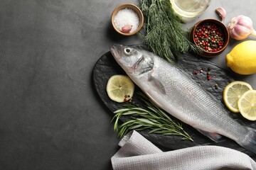 Fresh raw seabass fish with spices on grey table, flat lay and space for text. Seafood delicacies